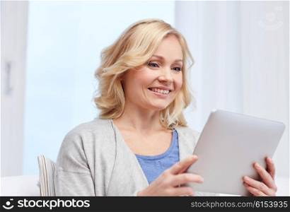 people, technology and internet concept - happy middle aged woman with tablet pc computer at home