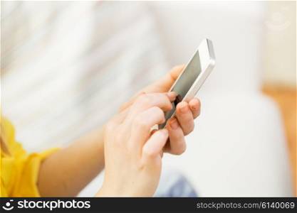people, technology and leisure concept - close up of hands texting on smartphone at home