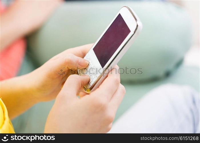 people, technology and leisure concept - close up of hands texting on smartphone at home