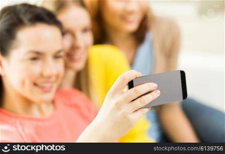 people, technology and leisure concept - close up of young women or teenage friends taking selfie with smartphones at home