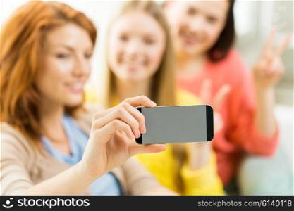 people, technology and leisure concept - close up of young women or teenage friends taking selfie with smartphones at home