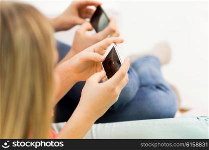 people, technology and leisure concept - close up of young women or teenage friends texting on smartphones at home