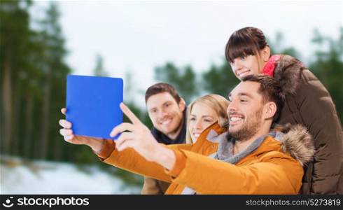 people, technology and leisure concept - happy friends taking selfie with tablet pc computer over winter outdoor background. friends with tablet pc taking selfie in winter