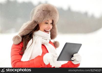 people, technology and leisure concept - happy smiling woman in winter fur hat with tablet pc computer outdoors. woman in winter fur hat with tablet pc outdoors