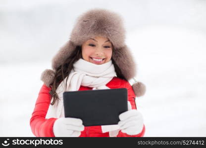 people, technology and leisure concept - happy smiling woman in winter fur hat with tablet pc computer outdoors. woman in winter fur hat with tablet pc outdoors