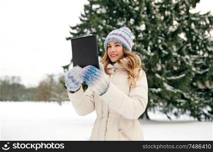 people, technology and leisure concept - happy smiling woman with tablet computer outdoors in winter. woman with tablet computer outdoors in winter