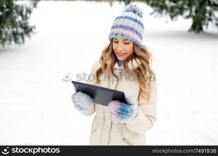 people, technology and leisure concept - happy smiling woman with tablet computer outdoors in winter. woman with tablet computer outdoors in winter