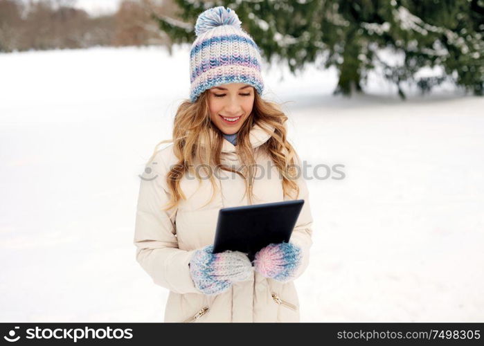 people, technology and leisure concept - happy smiling woman with tablet computer outdoors in winter. woman with tablet computer outdoors in winter