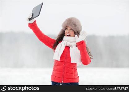 people, technology and leisure concept - happy woman in winter fur hat with tablet pc computer outdoors. woman in winter fur hat with tablet pc outdoors