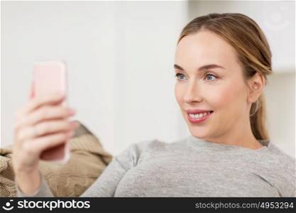 people, technology and leisure concept - happy woman taking selfie with smartphone at home. happy woman taking selfie with smartphone at home