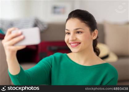 people, technology and leisure concept - happy young asian woman taking selfie on smartphone at home