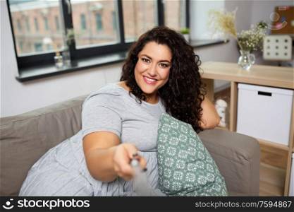people, technology and leisure concept - happy young woman lying on sofa and taking selfie at home. happy woman taking selfie at home