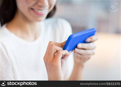 people, technology and lifestyle concept - close up of woman with smartphone at cafe