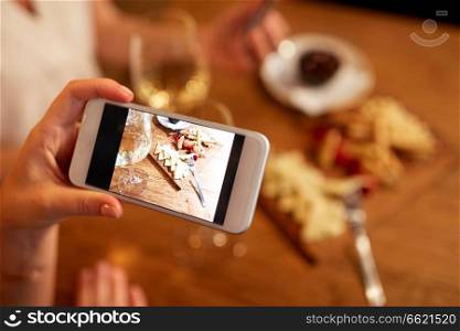 people, technology and lifestyle concept - hand picturing food by smartphone at wine bar. hand picturing food by smartphone at wine bar