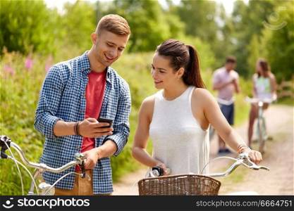 people, technology and lifestyle concept - happy couple with smartphone and bicycles in summer. couple with smartphone and bicycles in summer