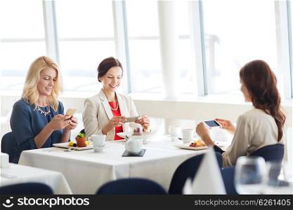 people, technology and lifestyle concept - happy women with smartphones taking picture of food at restaurant