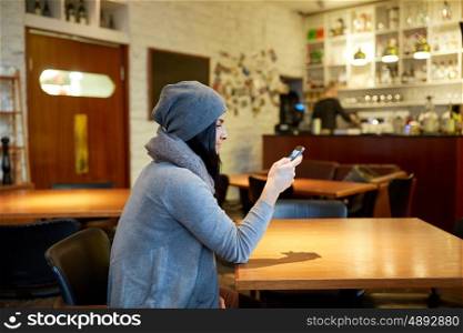 people, technology and lifestyle concept - smiling young woman with smartphone at cafe
