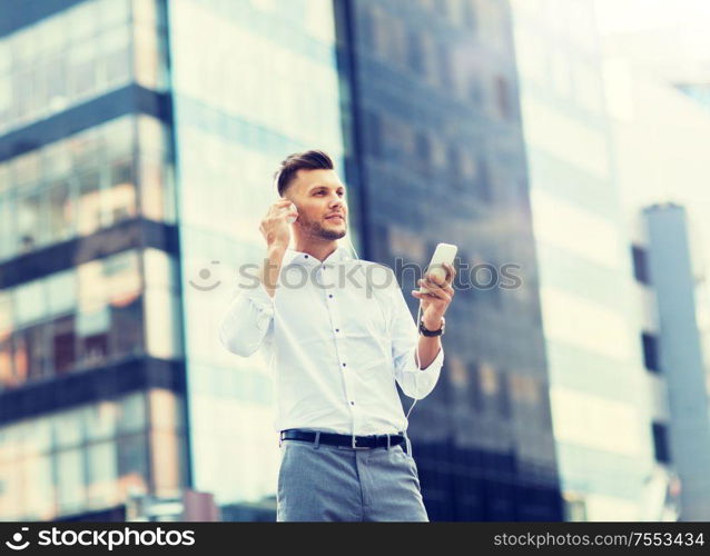 people, technology and lifestyle - happy young man with headphones and smartphone listening to music in city. man with headphones and smartphone listening music