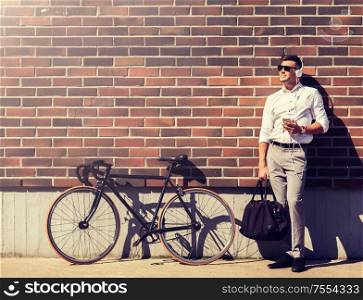 people, technology and lifestyle - happy young man with headphones, smartphone and bicycle listening to music in city. man with headphones, smartphone and bicycle