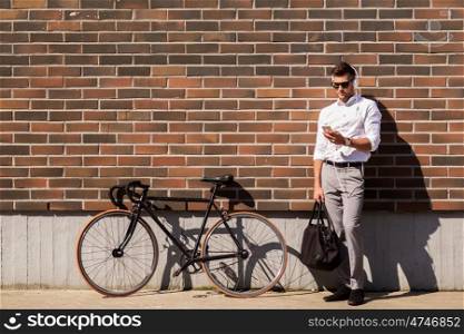 people, technology and lifestyle - young man with headphones, smartphone and bicycle listening to music in city