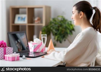 people, technology and online communication concept - happy young woman with laptop computer having video call or virtual birthday party at home. woman with laptop having virtual birthday party