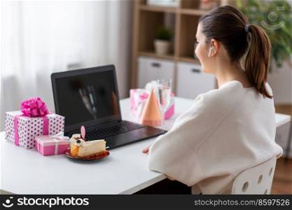 people, technology and online communication concept - happy young woman with laptop computer having video call or virtual birthday party at home. woman with laptop having virtual birthday party