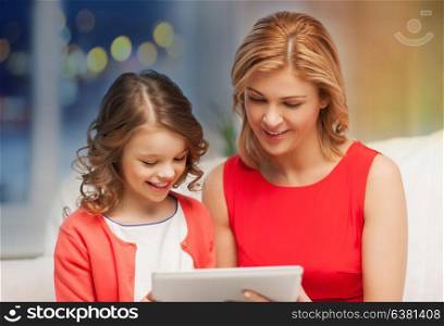 people, technology, christmas and family concept - mother and daughter with tablet pc computer over festive lights background. mother and daughter with tablet pc at home