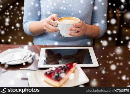 people, technology, christmas and winter concept - woman with coffee cup, tablet pc computer and berry cake on table over snow