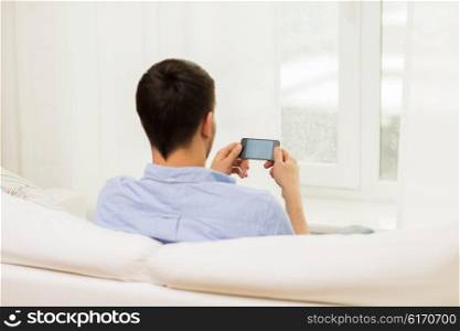 people, technology, communication and internet concept - close up of man with smartphone at home