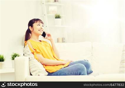 people, technology, communication and leisure concept - happy young asian woman calling on smartphone at home. happy asian woman calling on smartphone at home. happy asian woman calling on smartphone at home