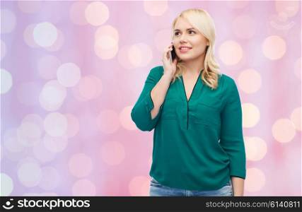 people, technology, communication and leisure concept - happy young woman calling on smartphone over pink holidays lights background