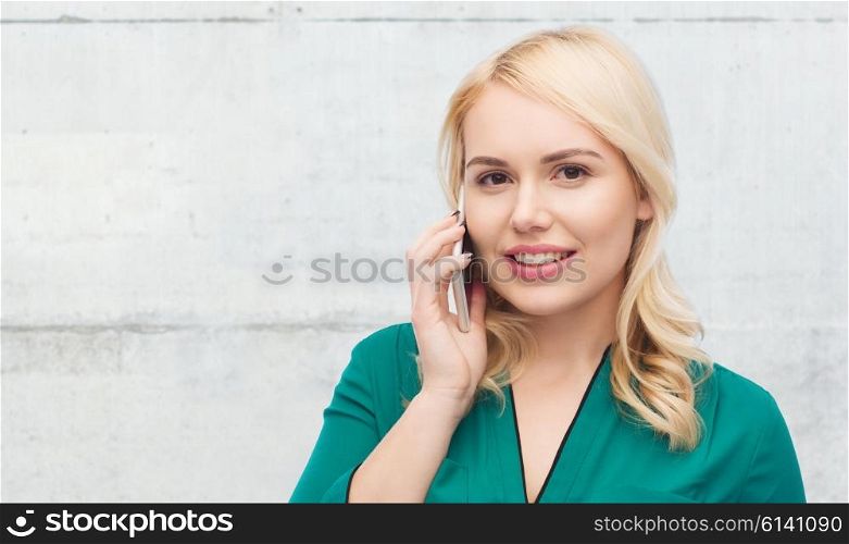 people, technology, communication and leisure concept - happy young woman calling on smartphone over gray concrete wall background