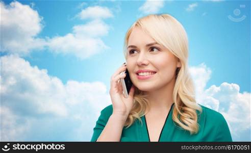 people, technology, communication and leisure concept - happy young woman calling on smartphone over blue sky and clouds background