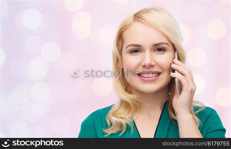 people, technology, communication and leisure concept - happy young woman calling on smartphone over pink holidays lights background