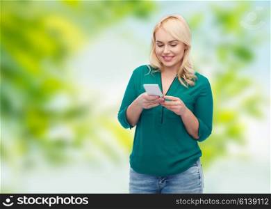 people, technology, communication and leisure concept - happy young woman with smartphone texting message over green natural background