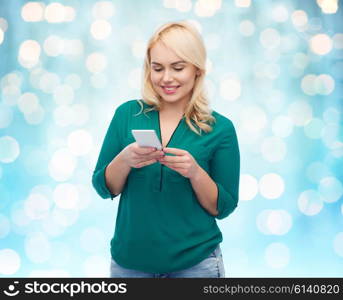 people, technology, communication and leisure concept - happy young woman with smartphone texting message over blue holidays lights background