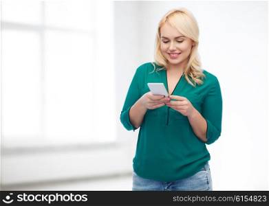 people, technology, communication and leisure concept - happy young woman with smartphone texting message over white room background