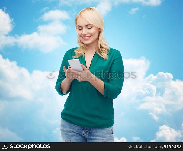 people, technology, communication and leisure concept - happy young woman with smartphone texting message over blue sky and clouds background