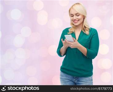 people, technology, communication and leisure concept - happy young woman with smartphone texting message over pink holidays lights background