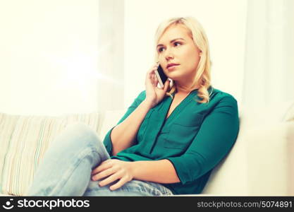 people, technology, communication and leisure concept - young woman calling on smartphone at home. young woman calling on smartphone at home