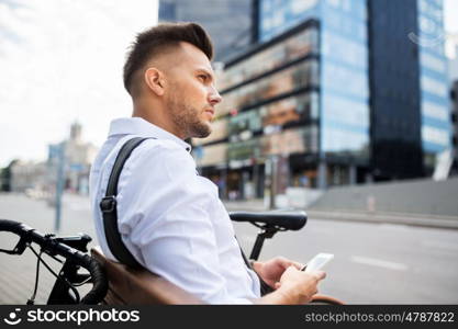 people, technology, communication and lifestyle - happy smiling young man with and bicycle sitting on city bench