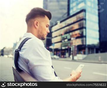 people, technology, communication and lifestyle - happy smiling young man with and bicycle sitting on city bench. man with smartphone and bicycle in city