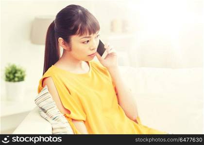 people, technology, communication and problem concept - young asian woman calling on smartphone at home. young asian woman calling on smartphone at home. young asian woman calling on smartphone at home