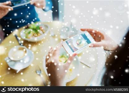 people, technology, eating and dating concept - close up of couple with smartphones picturing food at cafe or restaurant