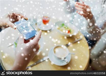 people, technology, eating and dating concept - close up of couple with smartphones picturing food at cafe or restaurant