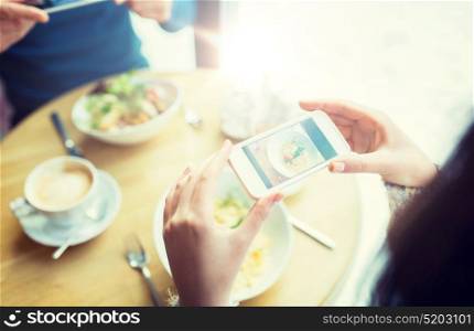 people, technology, eating and dating concept - close up of couple with smartphones picturing food at cafe or restaurant. close up of couple picturing food by smartphone