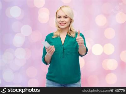 people, technology, gesture, communication and leisure concept - happy young woman with smartphone texting message over pink holidays lights background