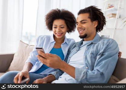 people, technology, internet and communication concept - happy couple with smartphones at home. happy couple with smartphones at home