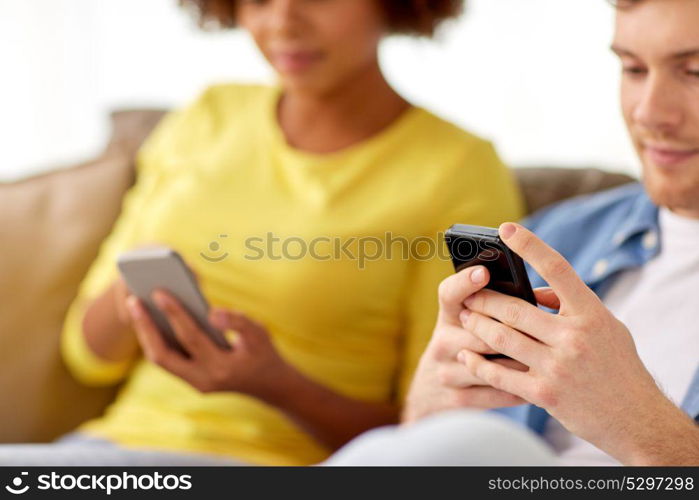 people, technology, internet and communication concept - happy couple with smartphones at home. happy couple with smartphones at home