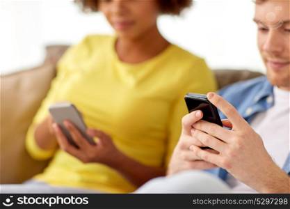 people, technology, internet and communication concept - happy couple with smartphones at home. happy couple with smartphones at home